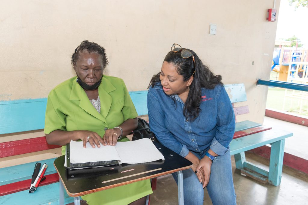 Charmaine Daniels (CEO of Digicel Foundation) observes as a teacher uses the Braille Machine